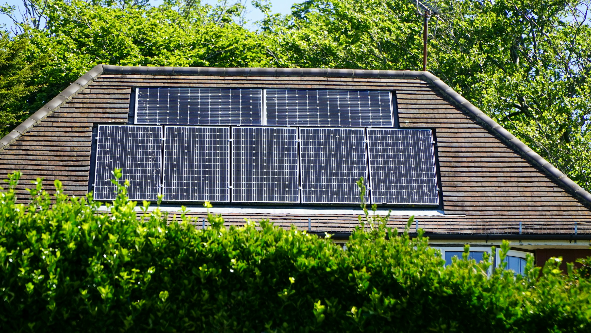 Wohnhausdach mit Solarmodulen und Bäumen · allgemeines Beispielmotiv